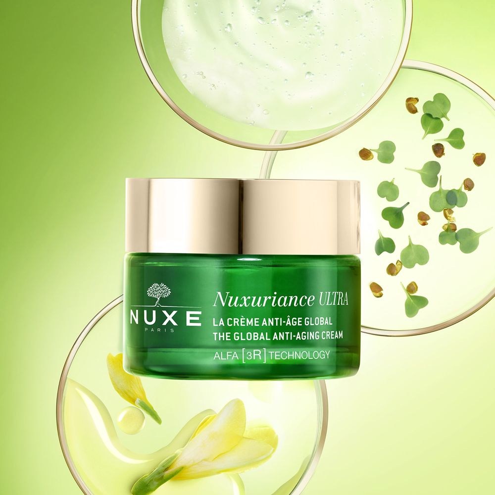 Vasetto verde con crema. Scritta: Nuxuriance Ultra, La Crème Anti-Âge Global. Logo albero. Coperchio dorato. Vetreria.