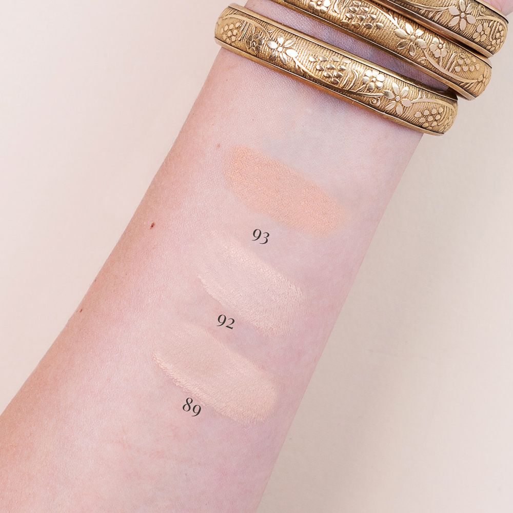Braccio con tre campioni di colore. Numeri colore 89, 92 e 93. Bracciale dorato. Pelle chiara. Colori cipria: chiaro, medio, scuro.