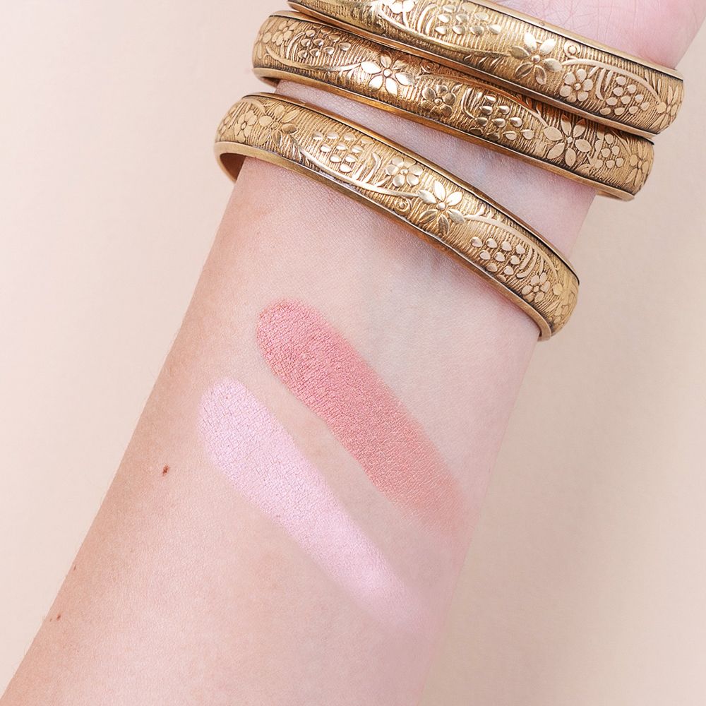 Braccio con due colori di blush. Strisce rosa chiaro e scuro sulla pelle. Bracciali dorati.