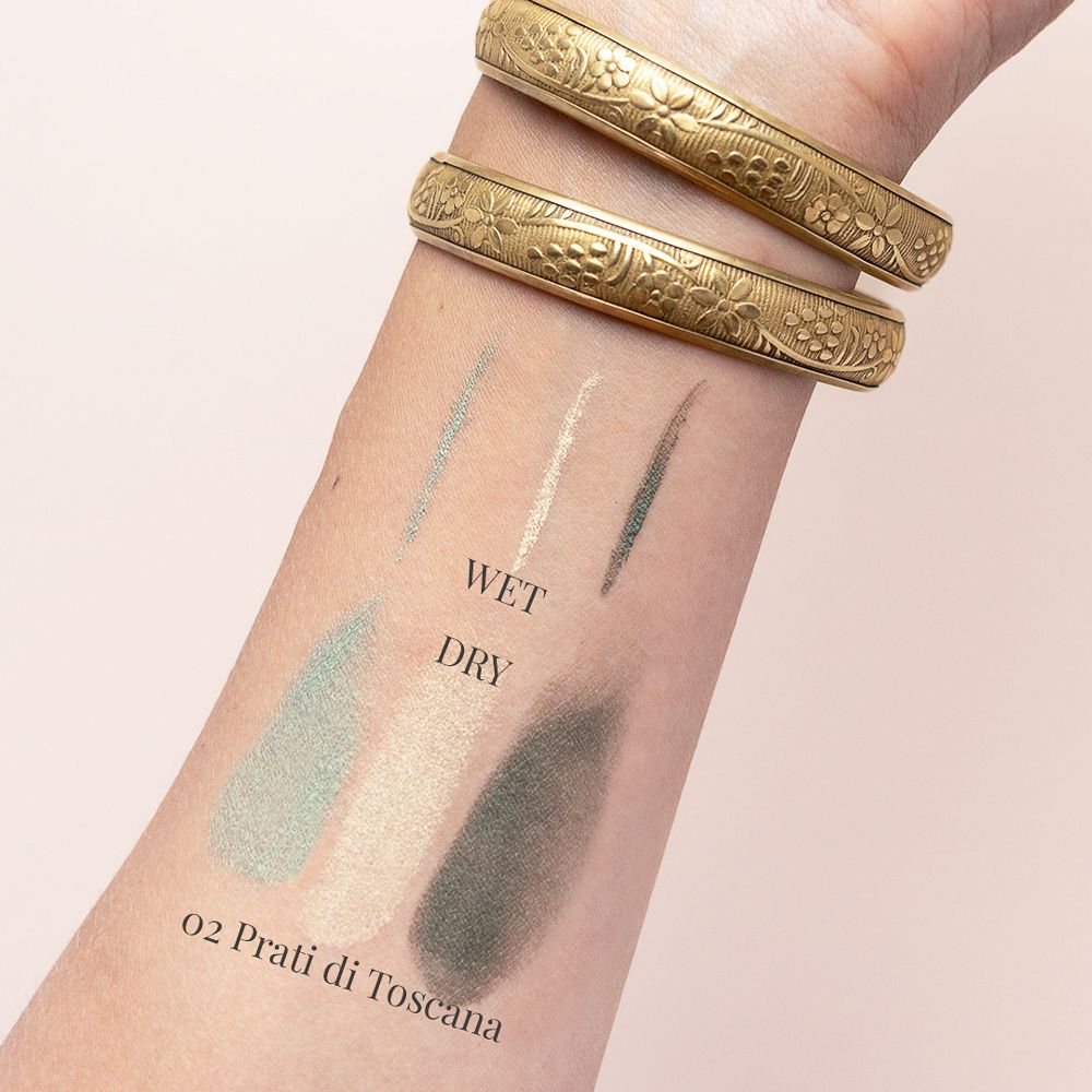 Braccio con tre tonalità di ombretto. Testo: Wet, Dry, 02 Prati di Toscana. Bracciali dorati.