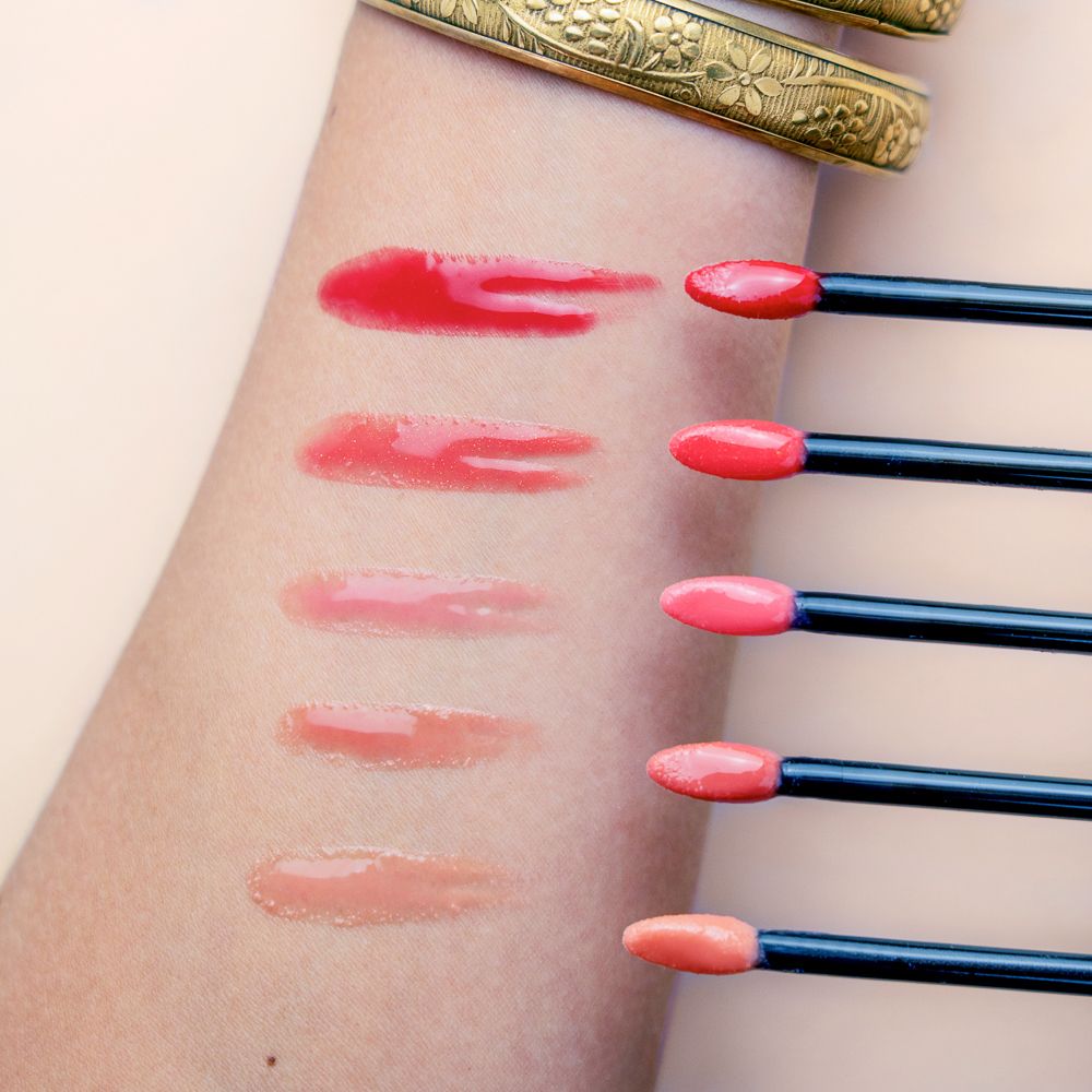 Braccio con campioni di rossetto. Diverse tonalità di lucidalabbra applicate. Applicatori visibili.