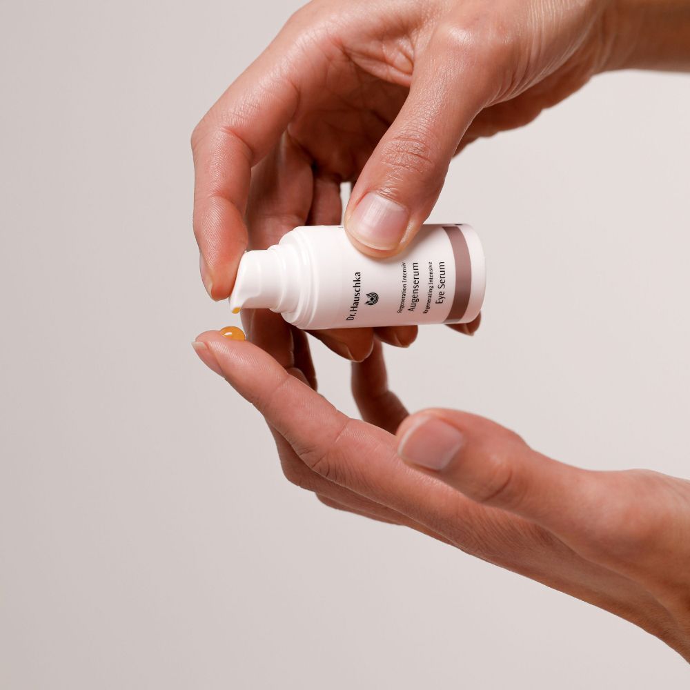 Mani che tengono un piccolo flacone bianco. Liquido giallo versato su un dito.