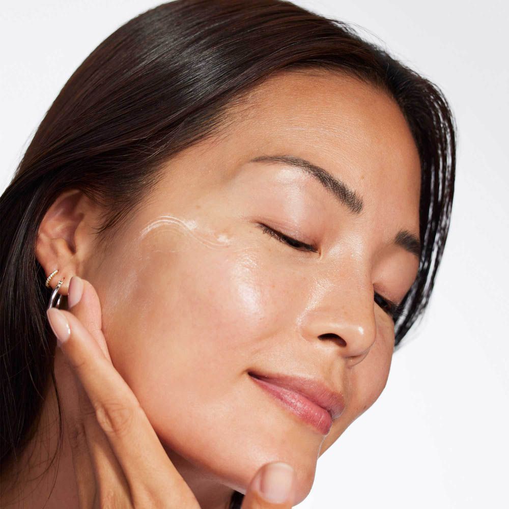 Una donna applica crema bianca sul viso.