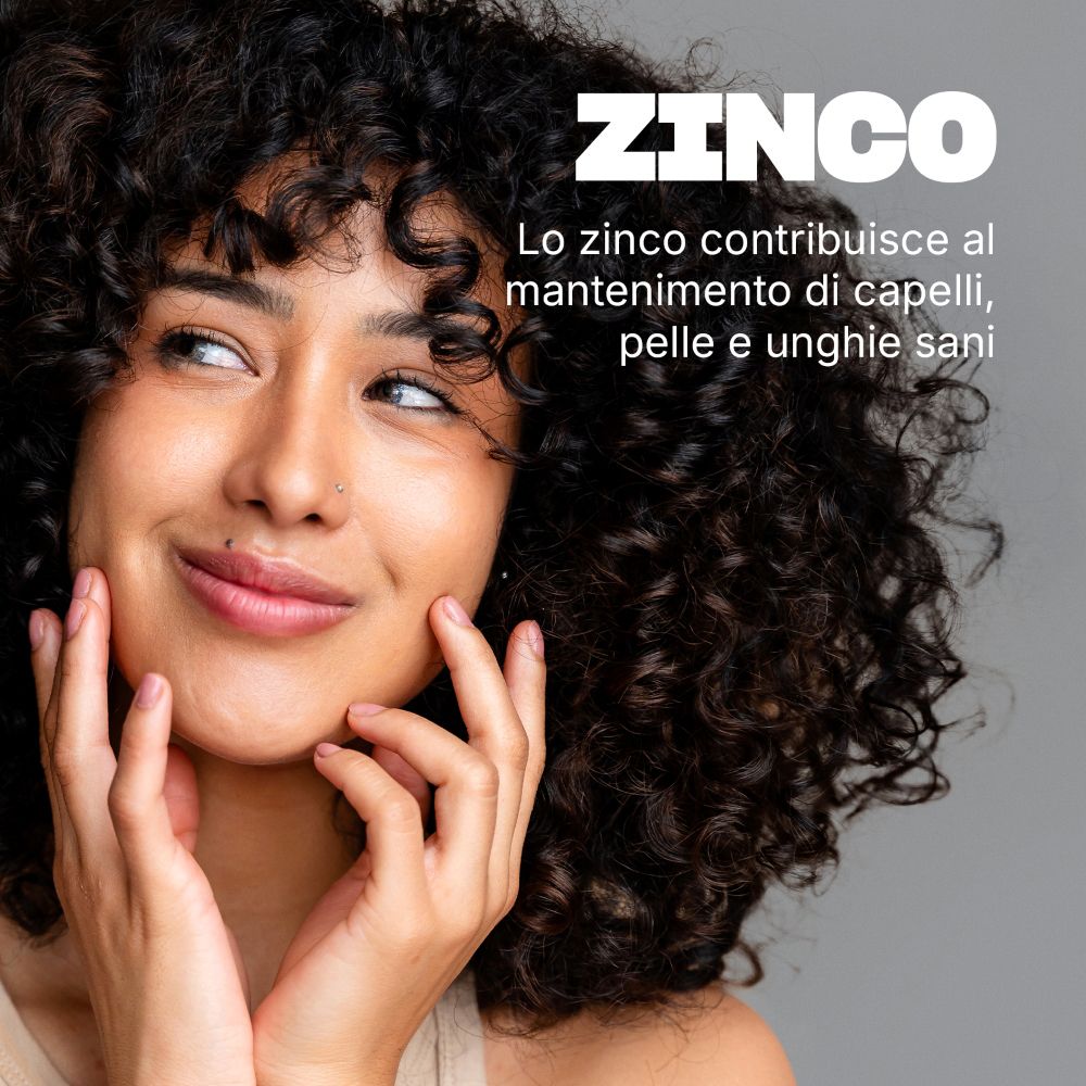 Donna con capelli ricci. Testo: ZINCO. Lo zinco contribuisce al mantenimento di capelli, pelle e unghie sani.