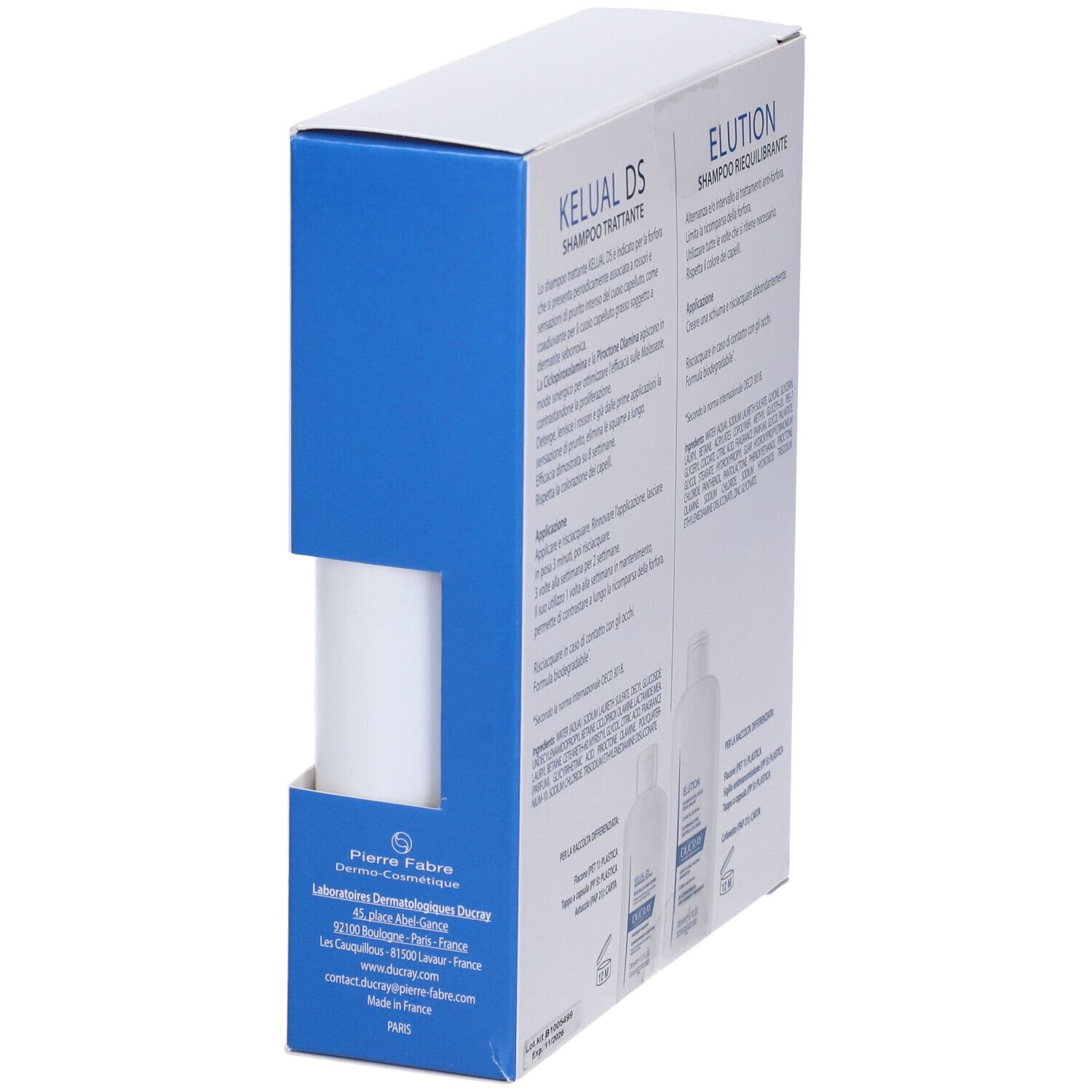 Confezione inclinata con informazioni sul prodotto. Scritte: Kelual DS ed Elution. Marchio: Ducray. Confezione blu e bianca.