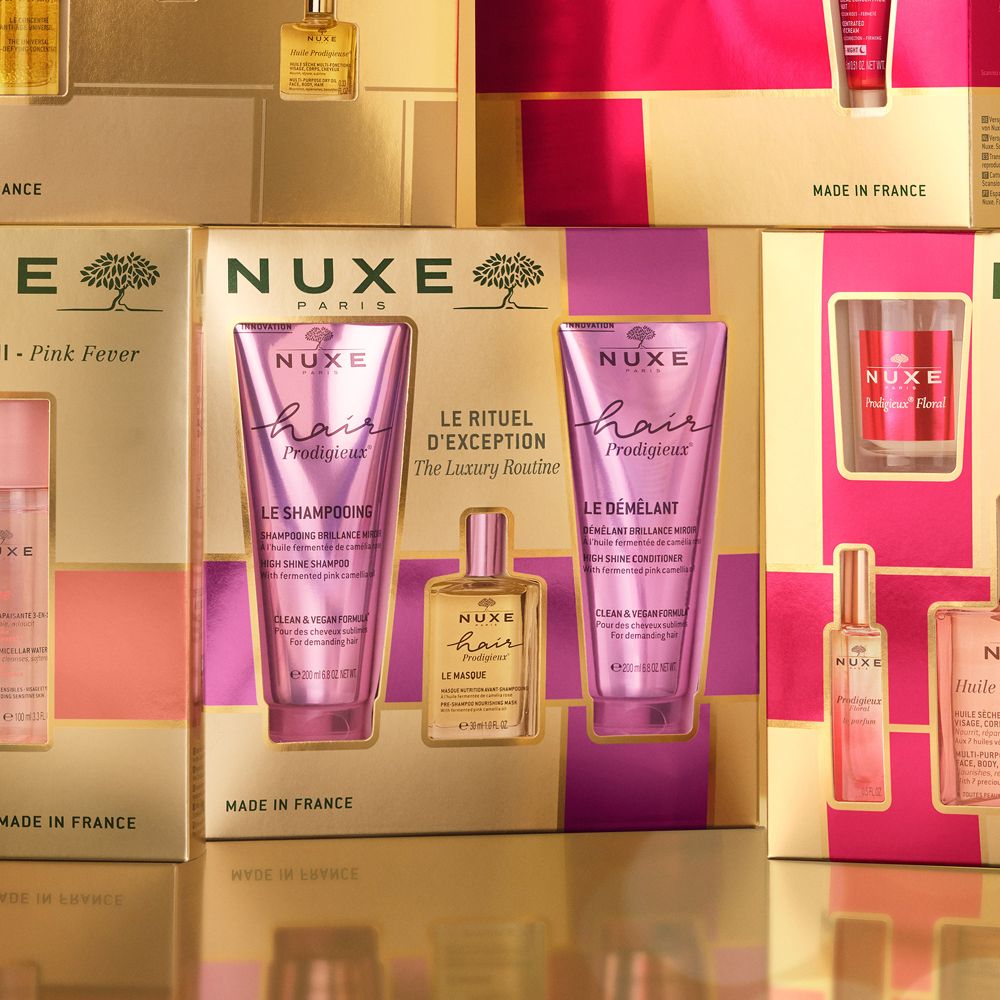 Diverse confezioni regalo Nuxe Hair Prodigieux. Due tubi e una bottiglia. Confezione oro e viola.