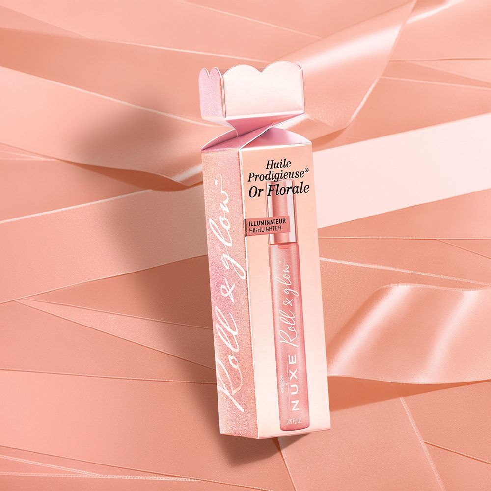 Confezione rosa con flacone roll-on. Scritta: Nuxe Roll & glow, Huile Prodigieuse Or Florale. Nastri rosa sullo sfondo.