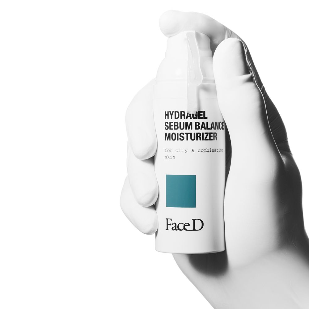 Prodotto bianco in una mano. Scritta: HYDRAGEL SEBUM BALANCE MOISTURIZER. Marchio: Face D.