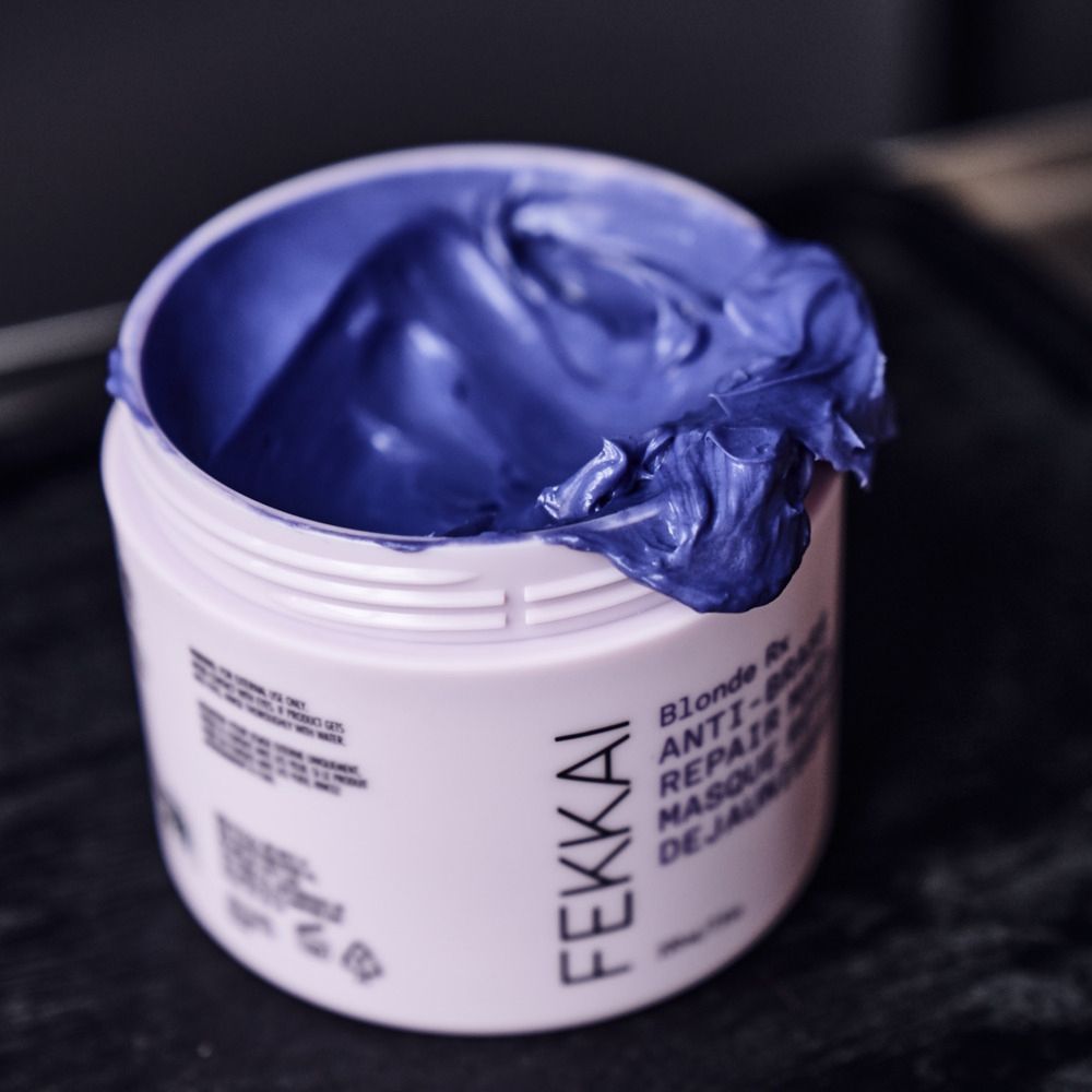 Barattolo aperto con maschera per capelli viola. Scritta: Fekkai, Blonde Rx, Anti-Brass Repair Mask.
