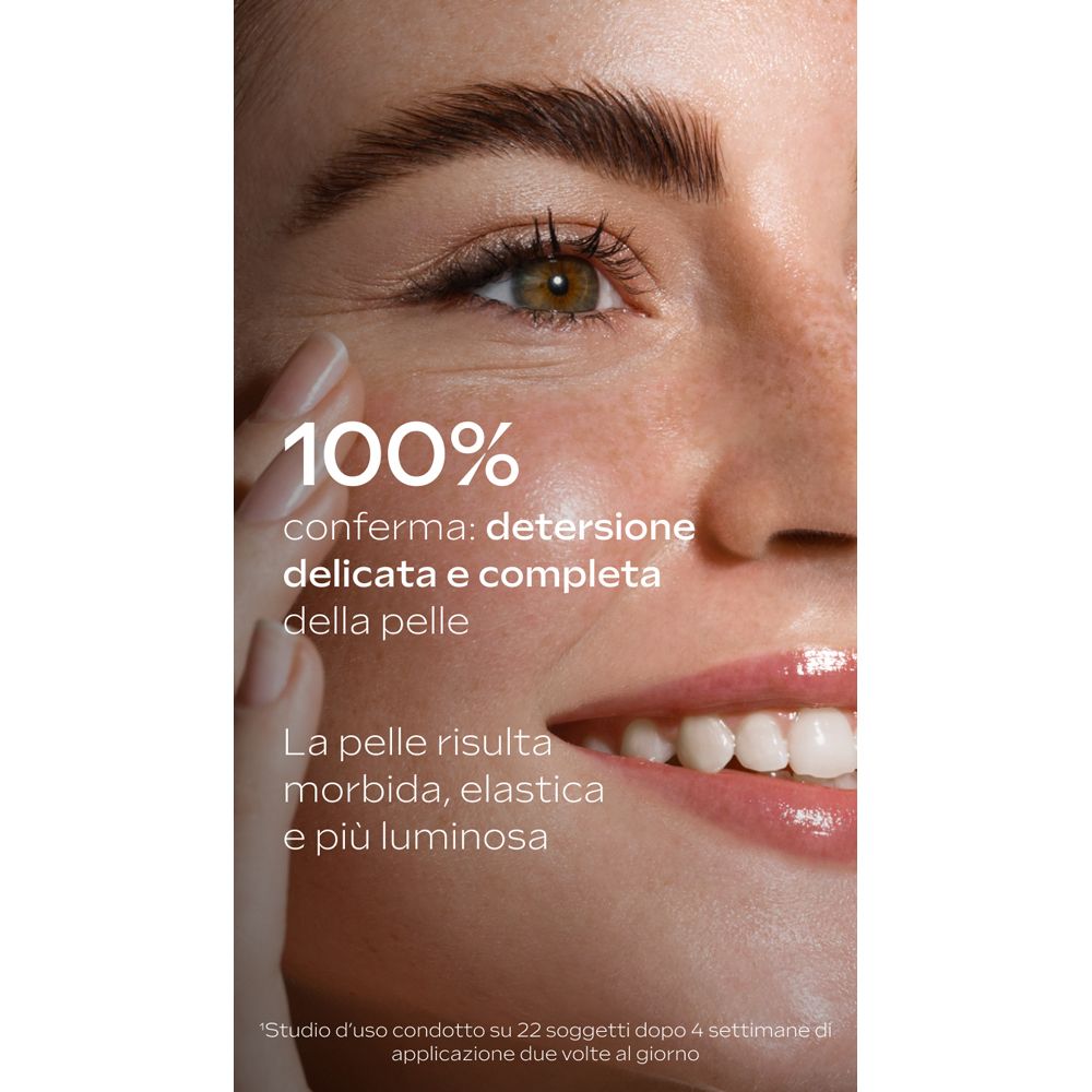 Primo piano di un viso sorridente. Testo: 100% conferma: detersione delicata e completa della pelle. La pelle risulta morbida, elastica e più luminosa.