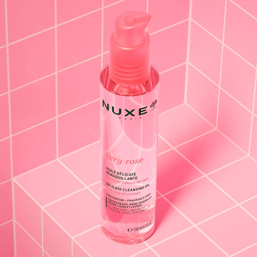 Flacone rosa con dosatore su piastrelle rosa. Scritte: Nuxe Paris, Very Rose, Huile Délicate Démaquillante, Delicate Cleansing Oil.