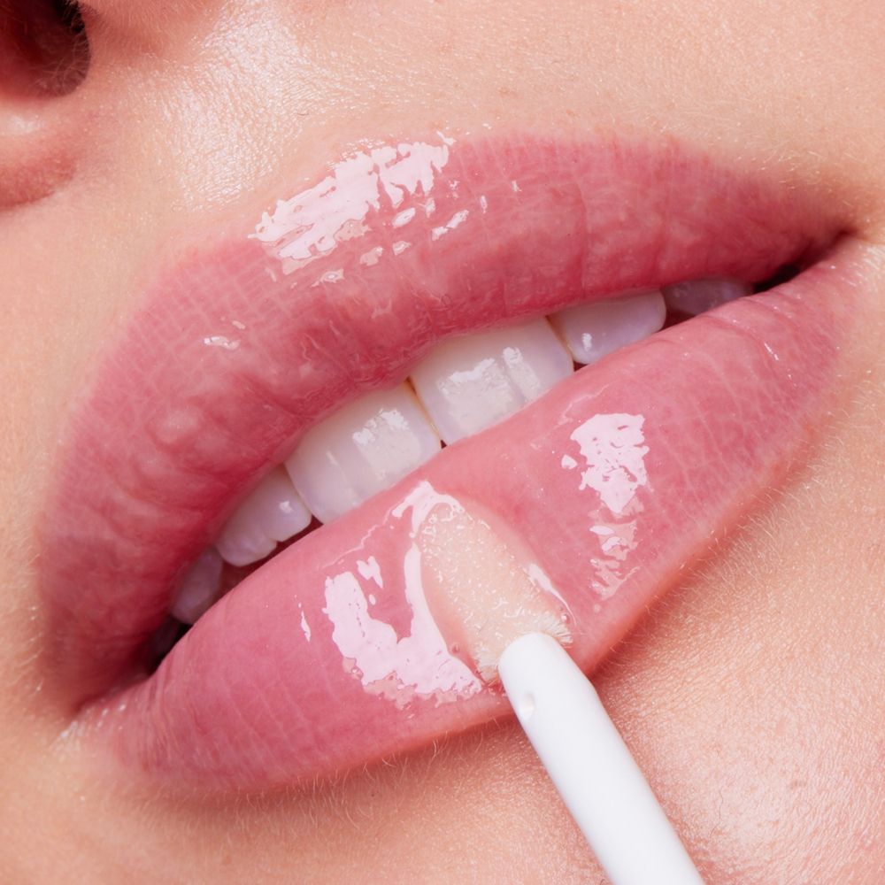 Primo piano di labbra con gloss. Visibile: texture lucida, applicatore.