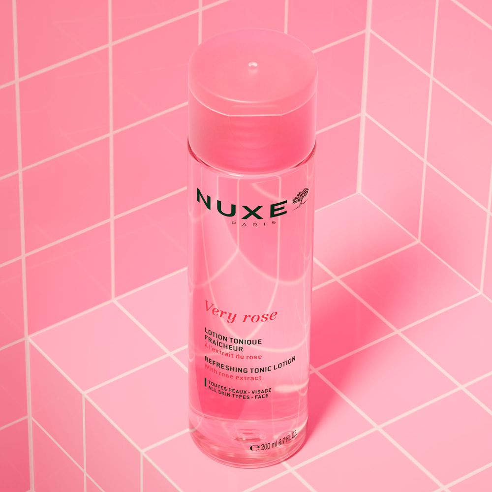 Flacone rosa con tappo rosa. Scritta: Nuxe Paris, Very Rose, Lotion Tonique Fraîcheur. Su piastrelle rosa.
