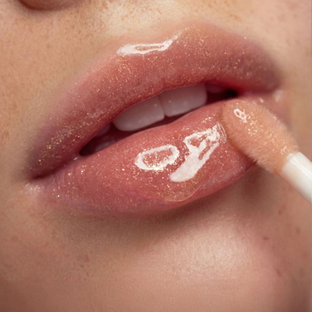 Applicatore con balsamo labbra dorato sulle labbra.