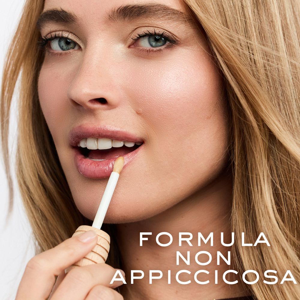 Donna applica balsamo labbra dorato con applicatore.