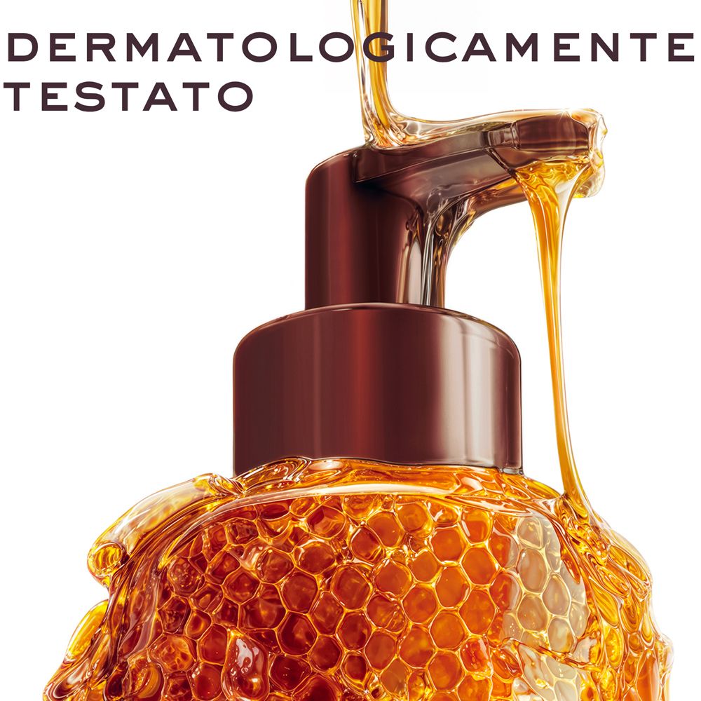Primo piano del dispenser, miele che cola su una struttura a nido d'ape.