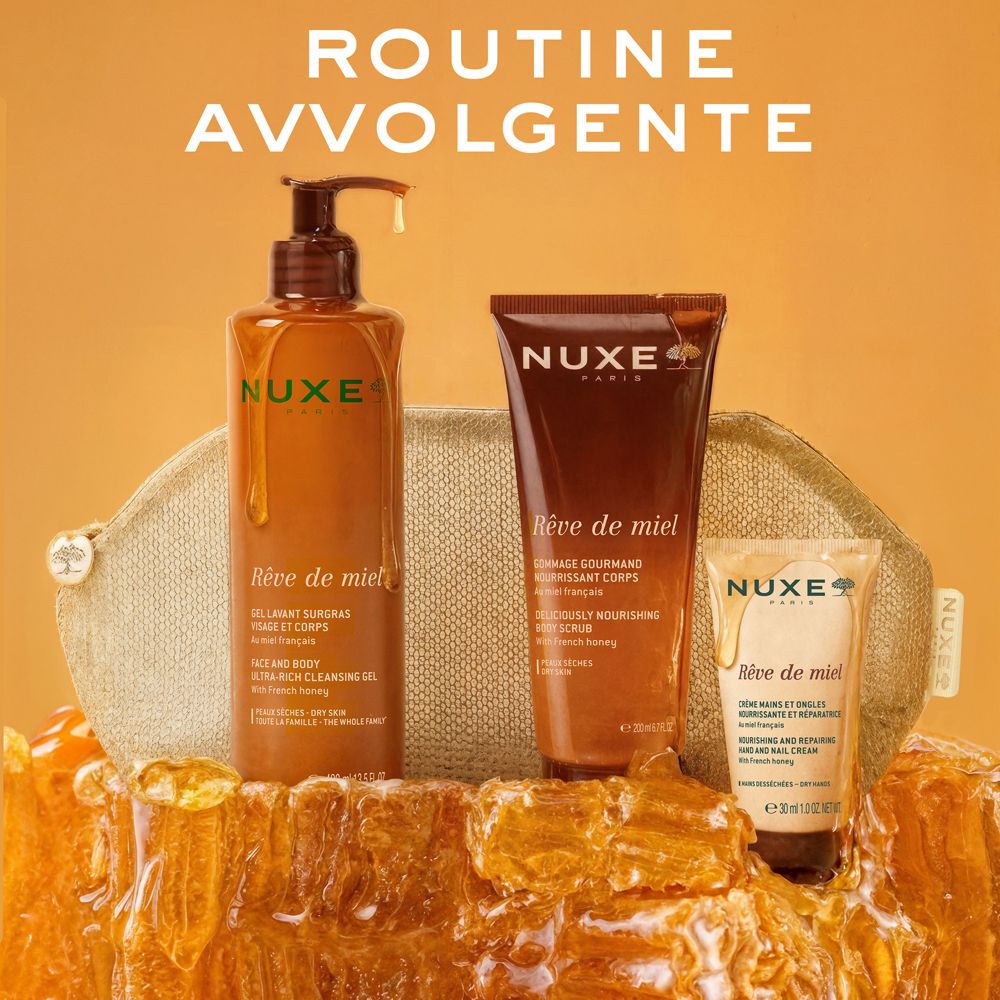 Gel doccia, scrub corpo e crema mani NUXE Rêve de miel davanti a uno sfondo di favi.