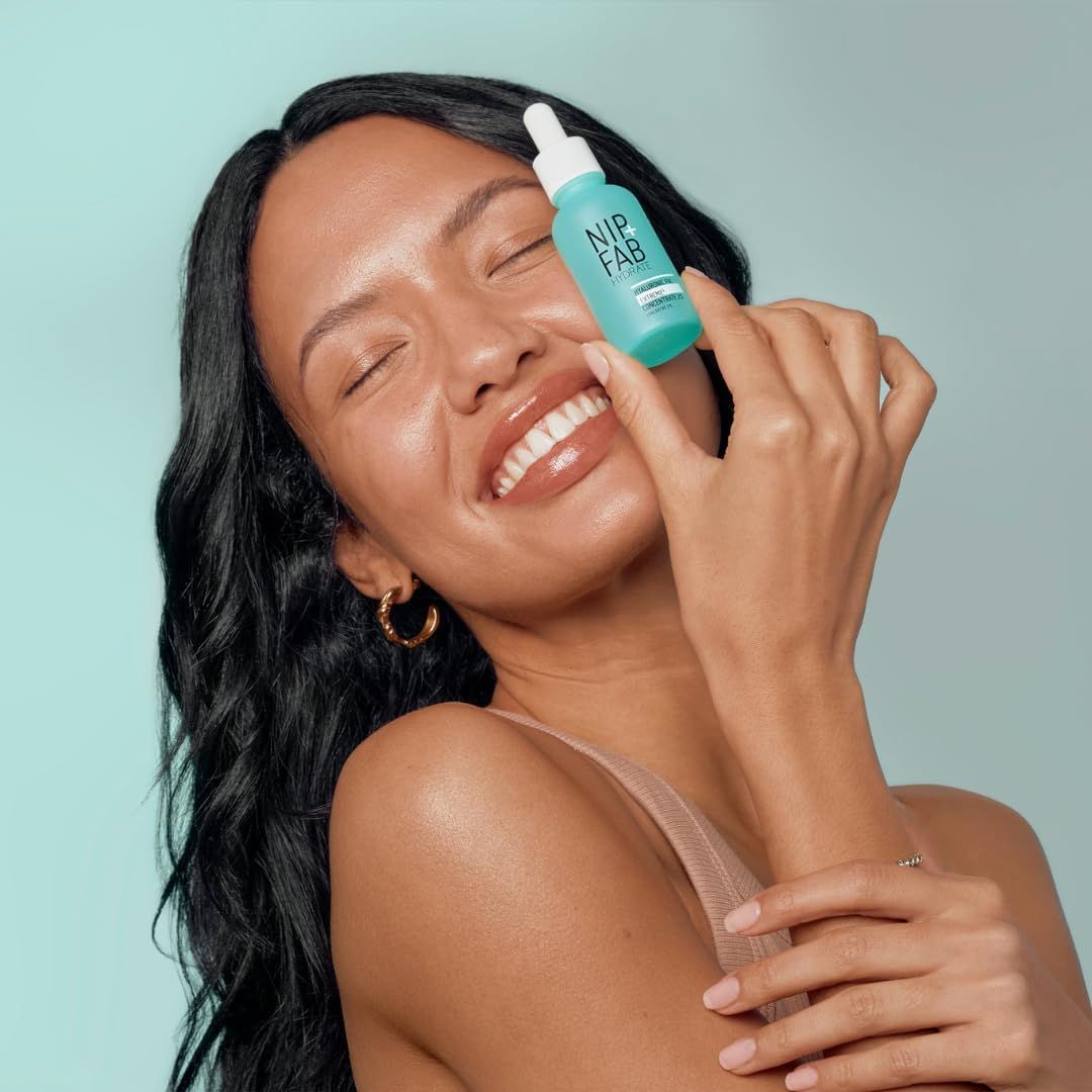 Donna che tiene in mano un flacone turchese. Scritta: NIP+FAB. Sorride con gli occhi chiusi.