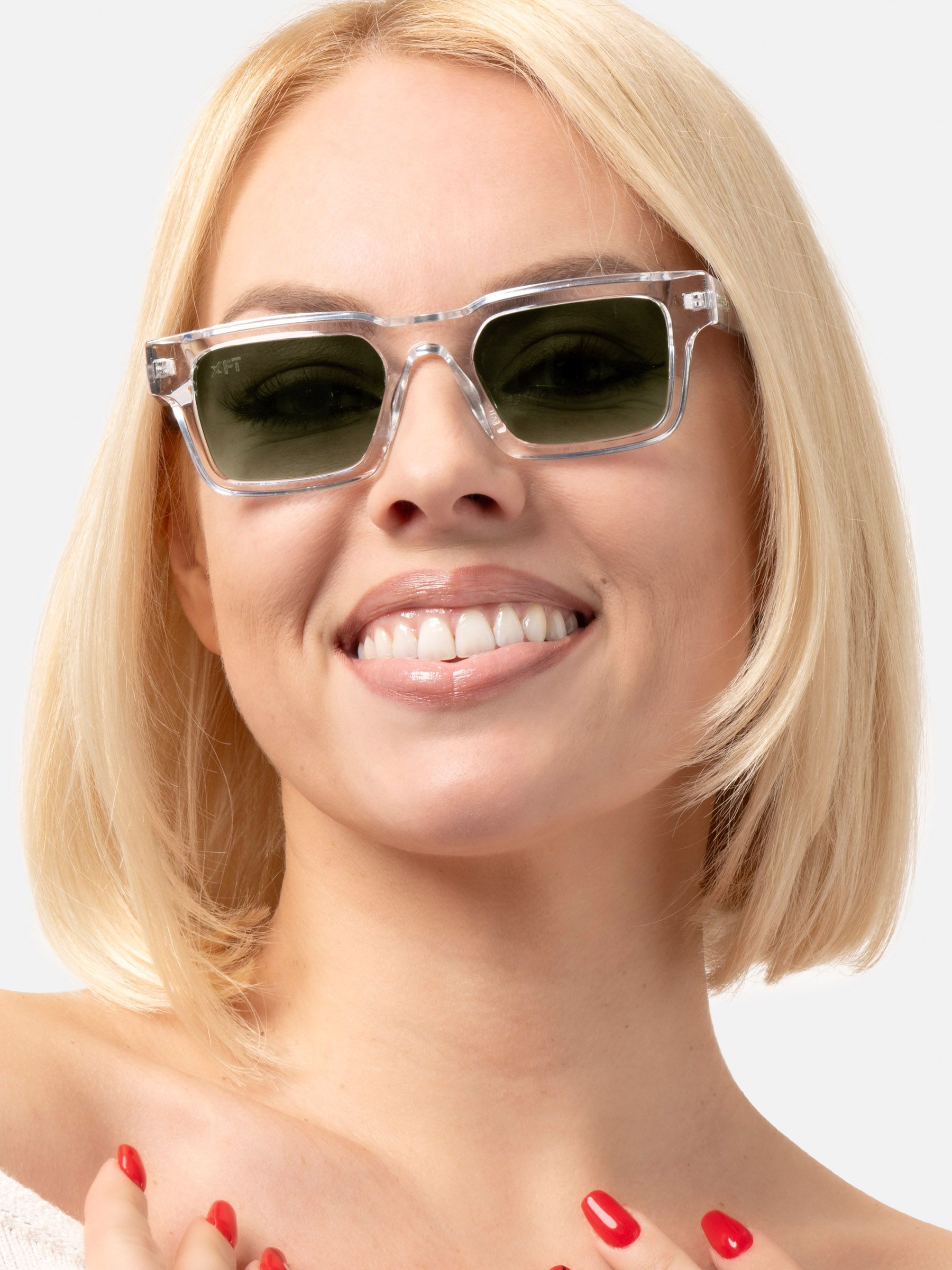 Donna con occhiali da sole trasparenti con lenti verdi. Forma rettangolare. Primo piano, sorridente.