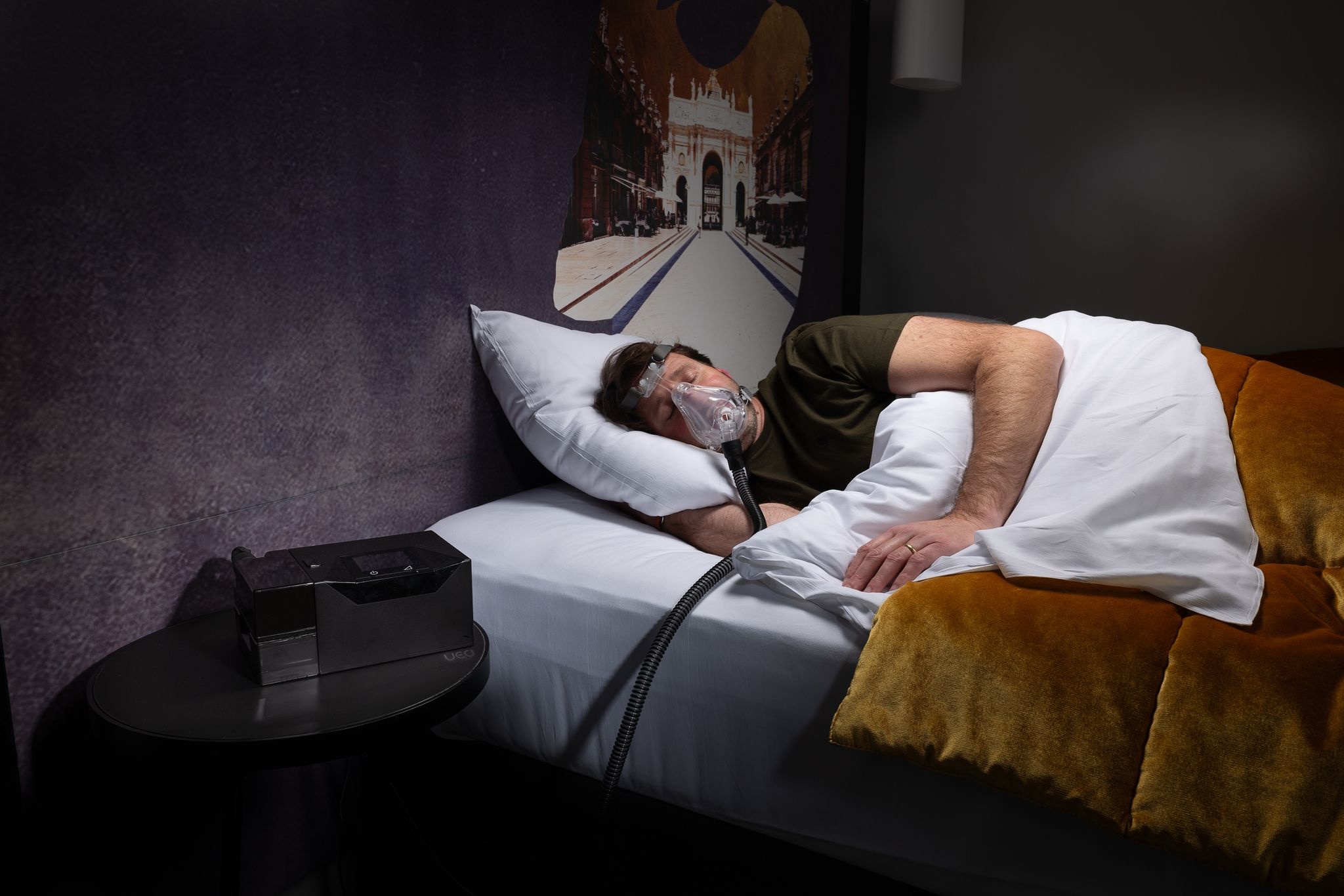 Uomo dorme con maschera APAP, dispositivo sul comodino.