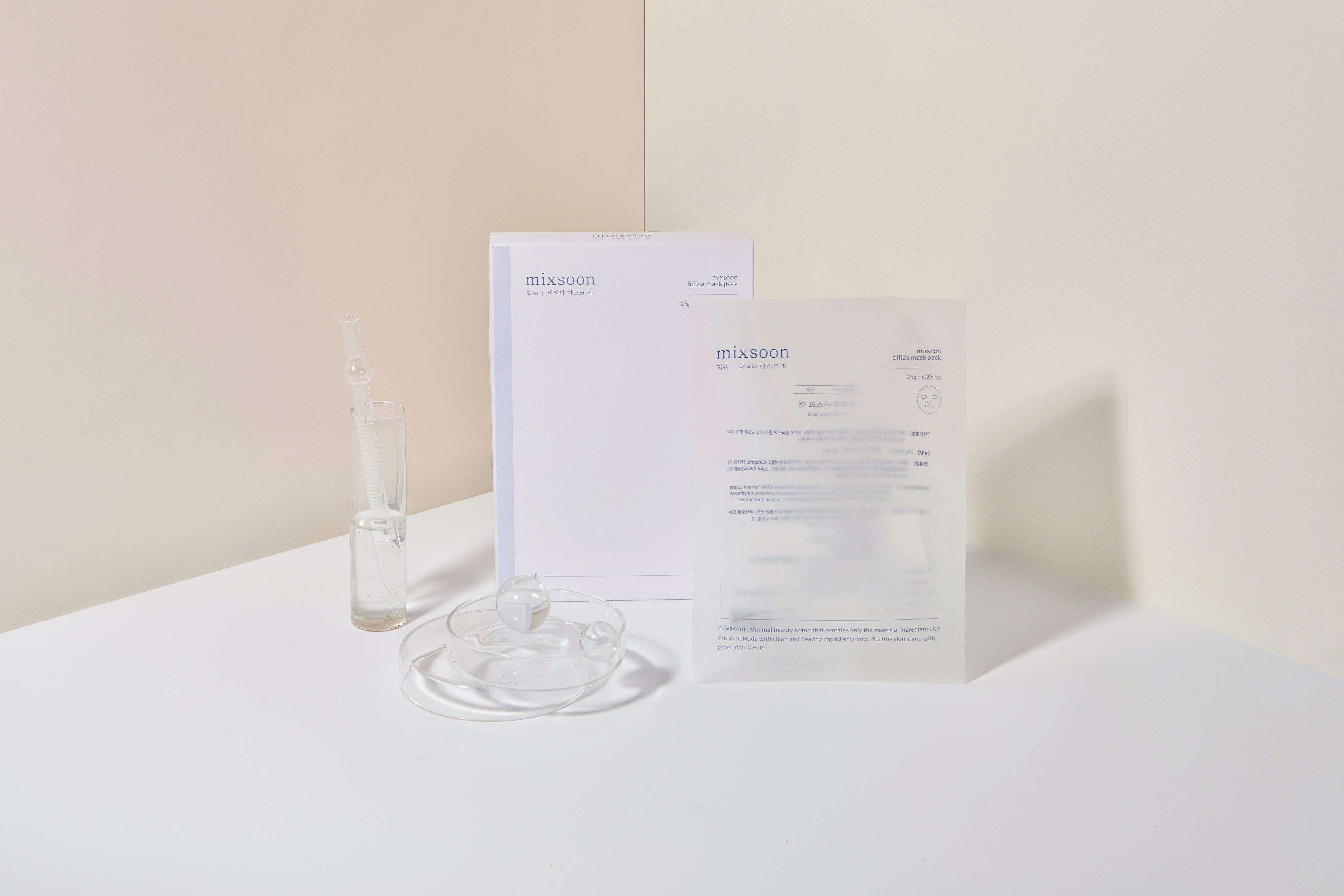 Confezione e accessori. Contenitore di vetro con liquido, coppetta, maschera e pila di carta.