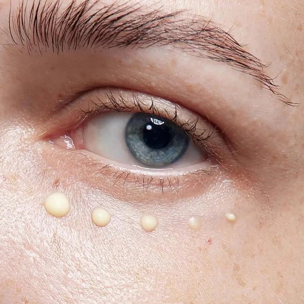 Occhio con gocce di crema. Pelle chiara, iride blu. Gocce di crema sotto l'occhio.