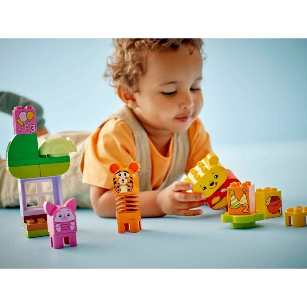 Bambino che gioca con LEGO DUPLO 10457. Set con personaggi di Winnie the Pooh, casa, albero e accessori. Il bambino tiene una figura.