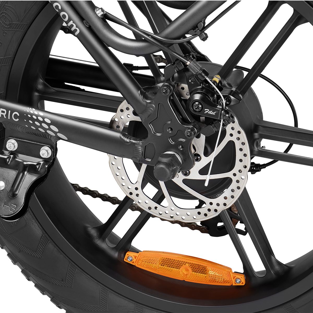 Primo piano della ruota posteriore di una e-bike. Freno a disco, catarifrangente e pneumatico visibili. Cerchio nero.