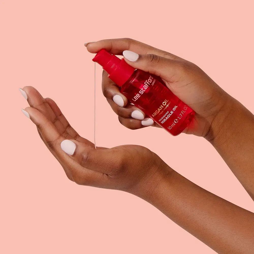 Mani che dosano Olio di Argan Lee Stafford da un flacone rosso.