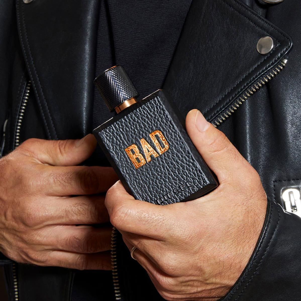 Uomo che tiene un flacone Diesel Bad Eau de Toilette in giacca di pelle.