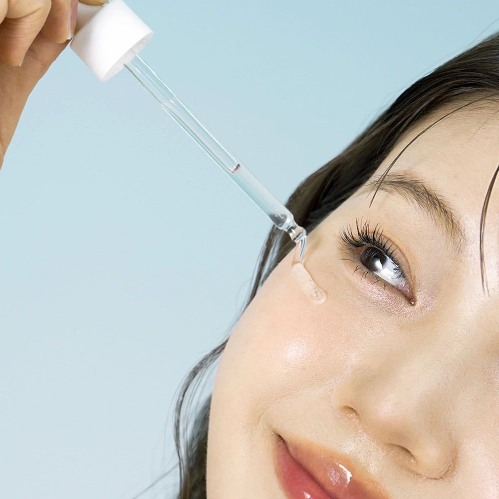 Donna con applicatore di siero. Il siero viene applicato sulla pelle. Sfondo blu.