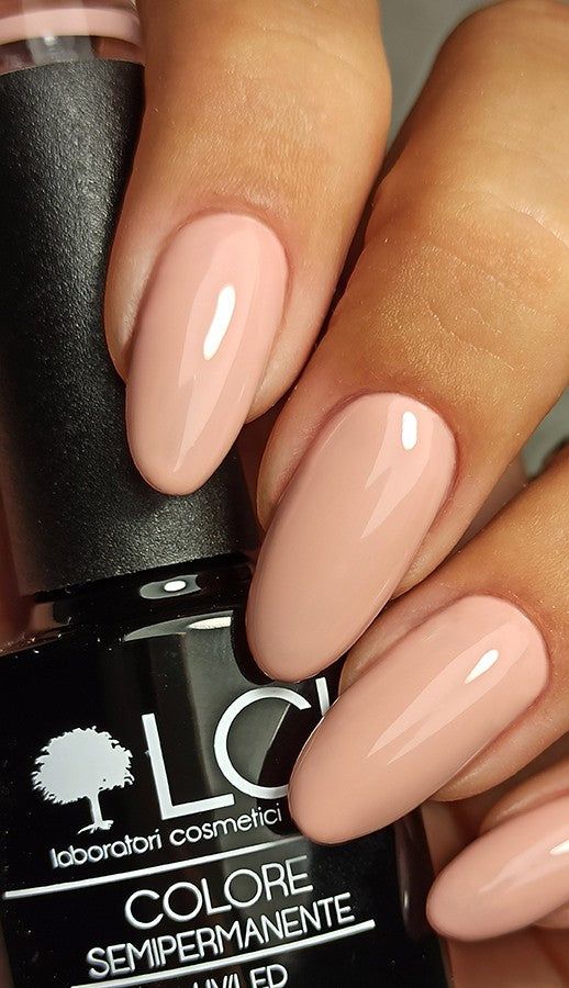 Mano con unghie smaltate rosa. Flacone di smalto con scritta LCI.