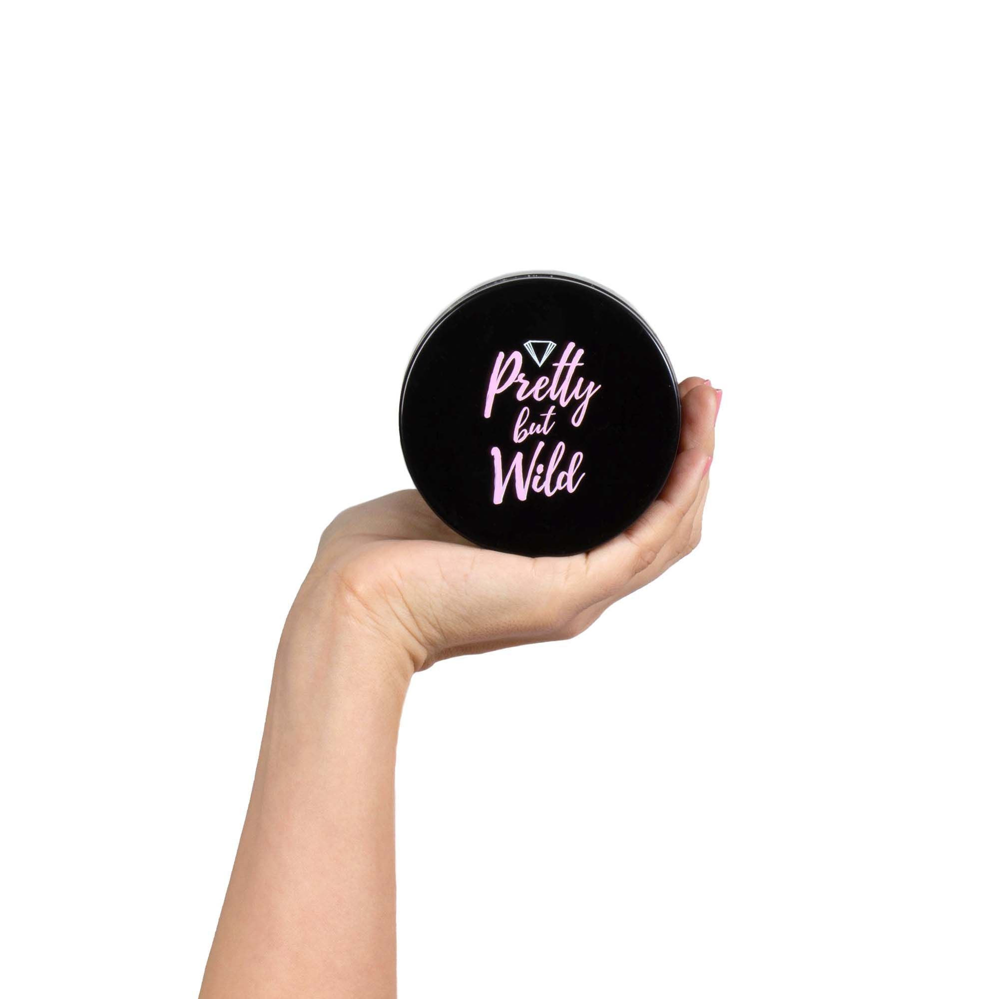 Mano che tiene un vaso nero con la scritta "Pretty but Wild".
