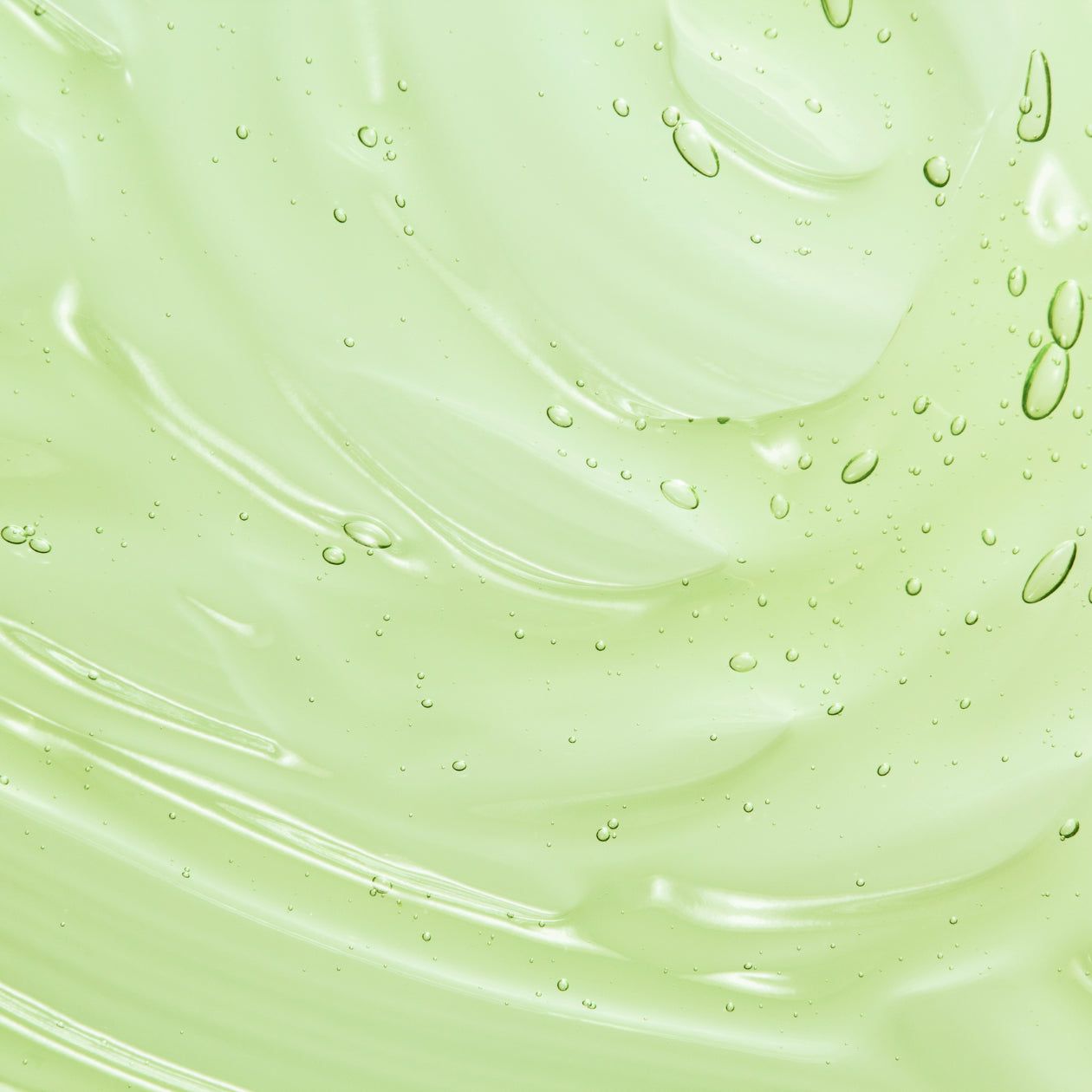 Primo piano di una sostanza trasparente simile a un gel con bolle. Colore verde chiaro, consistenza ondulata.