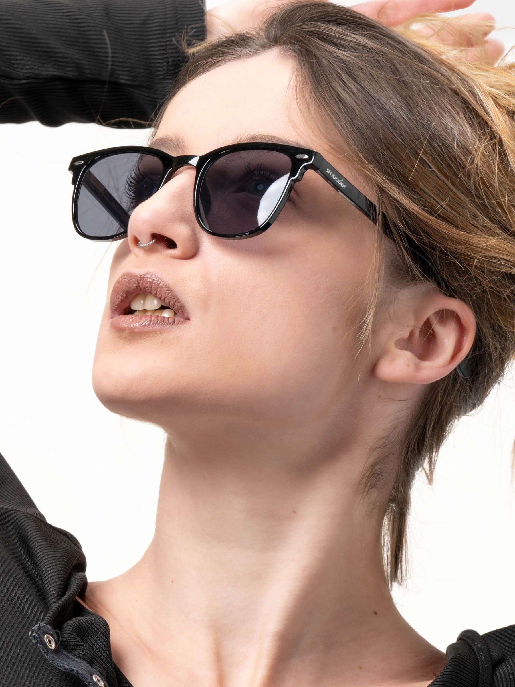 Persona che indossa occhiali da sole neri. Il marchio 'Smooder' è visibile sull'asta.