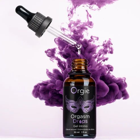 Flacone marrone con etichetta nera. Testo: Orgie, Orgasm Drops, Gel intimo, clitoral arousal. Pipetta. Fumo viola sullo sfondo.