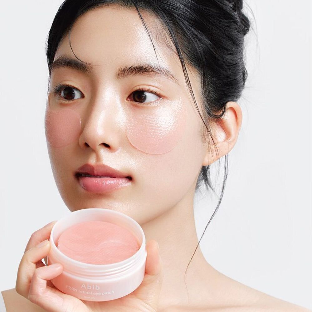 Donna che tiene un barattolo aperto di cerotti per gli occhi. Cerotti per gli occhi applicati sulla pelle. Barattolo con scritta Abib.