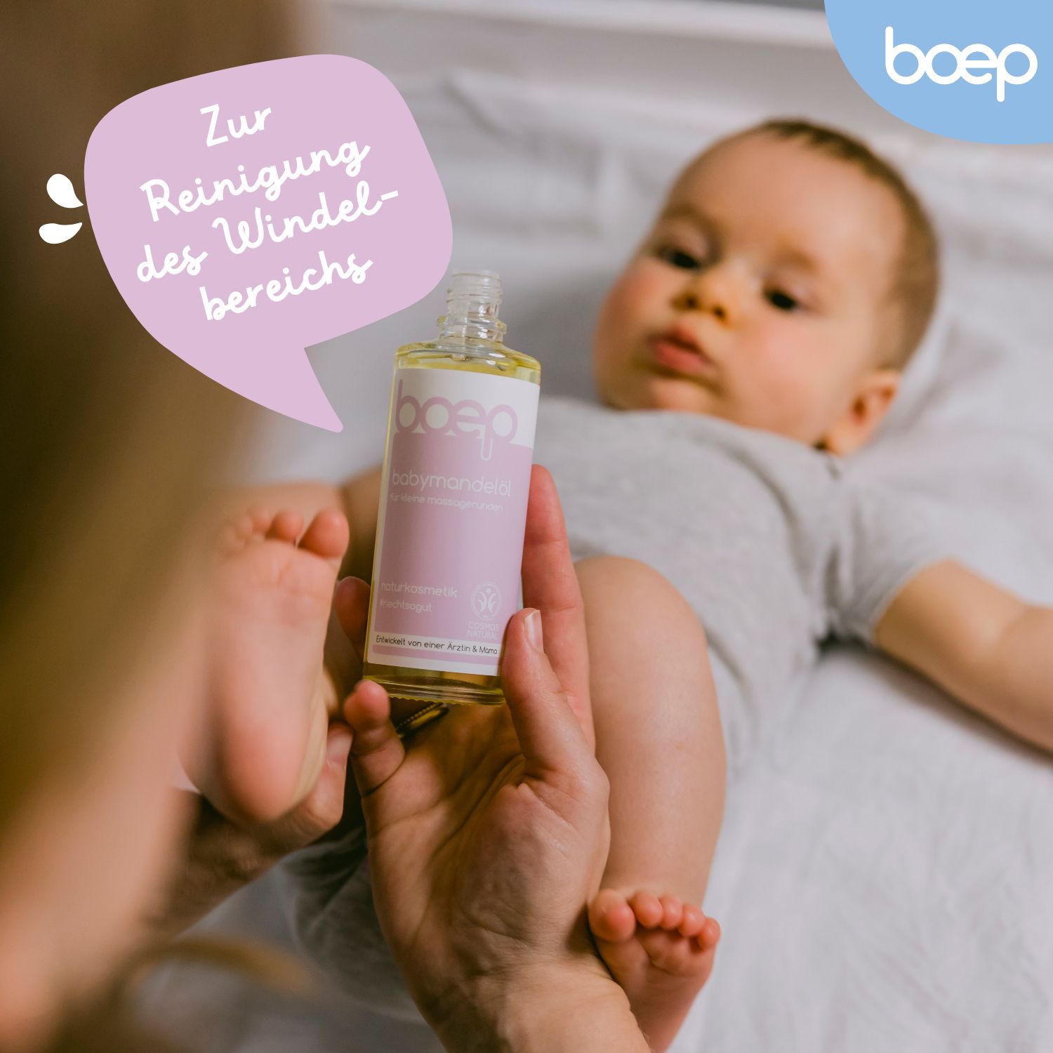 Bambino supino, flacone di olio di mandorle per bambini. Logo: boep. Testo: Per la pulizia della zona del pannolino.