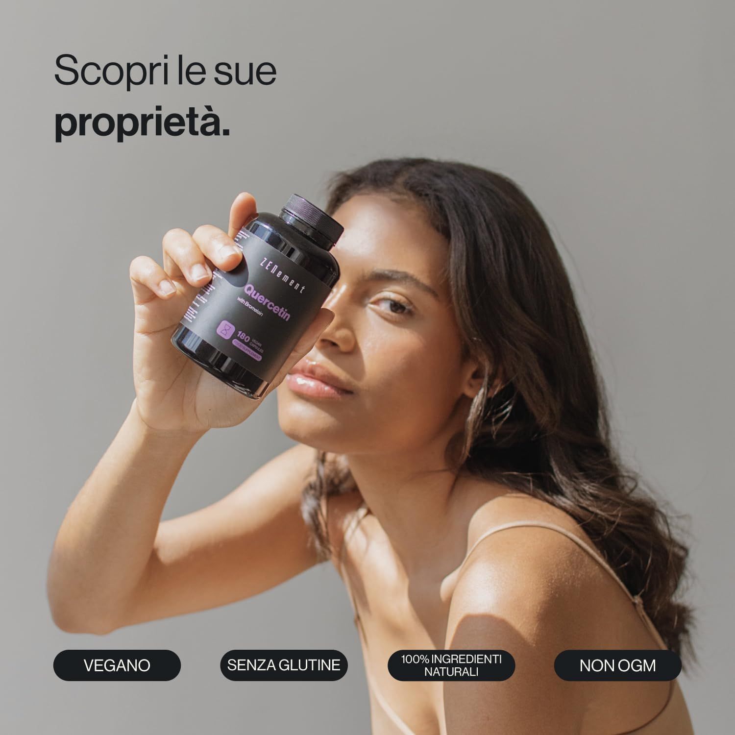 Donna tiene in mano una bottiglia di capsule di quercetina Zenement. Scritte: Vegano, Senza glutine, 100% ingredienti naturali, Non OGM.