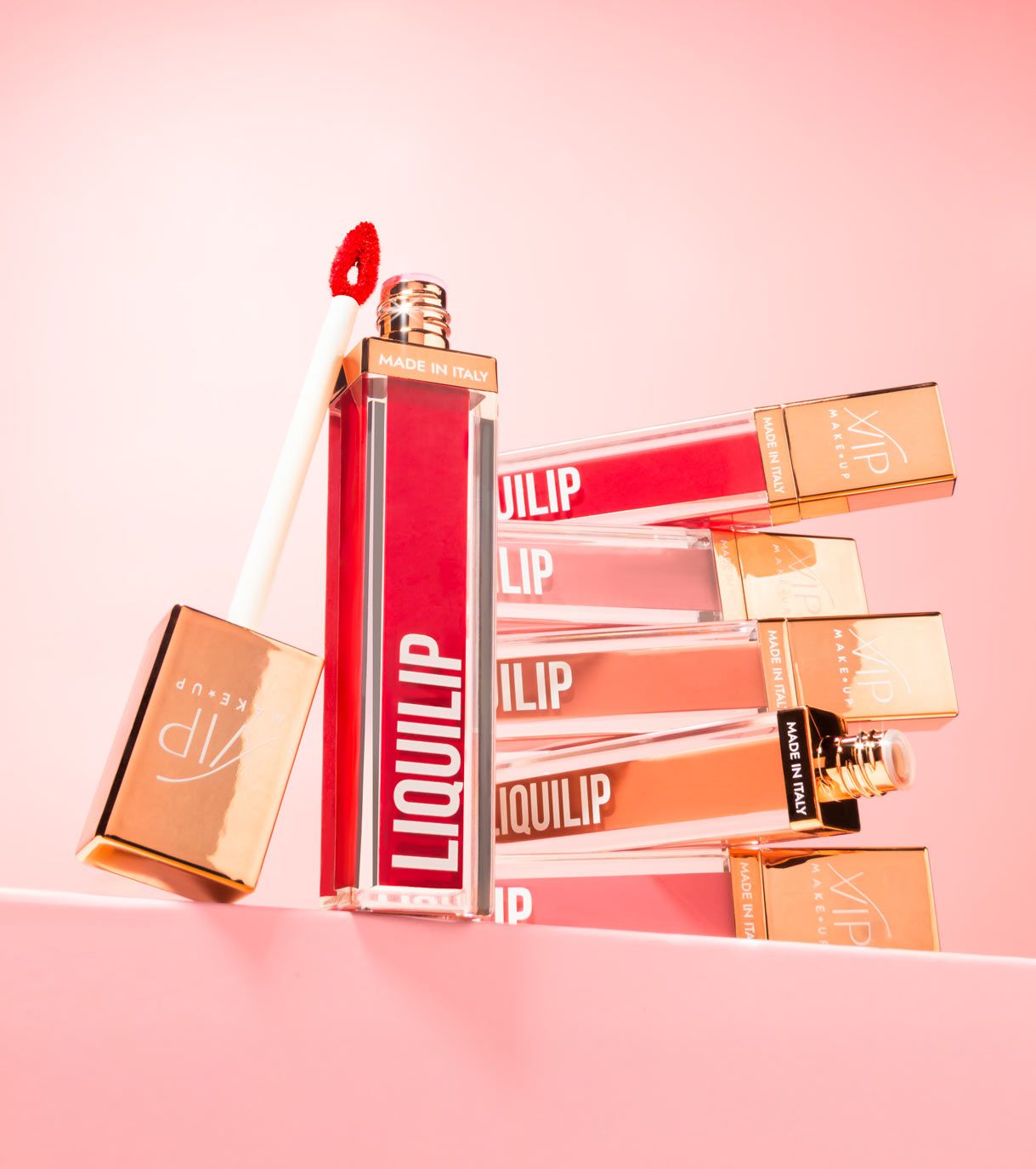 Sei rossetti liquidi in varie tonalità di rosso con tappi dorati. Un rossetto è aperto e mostra l'applicatore.