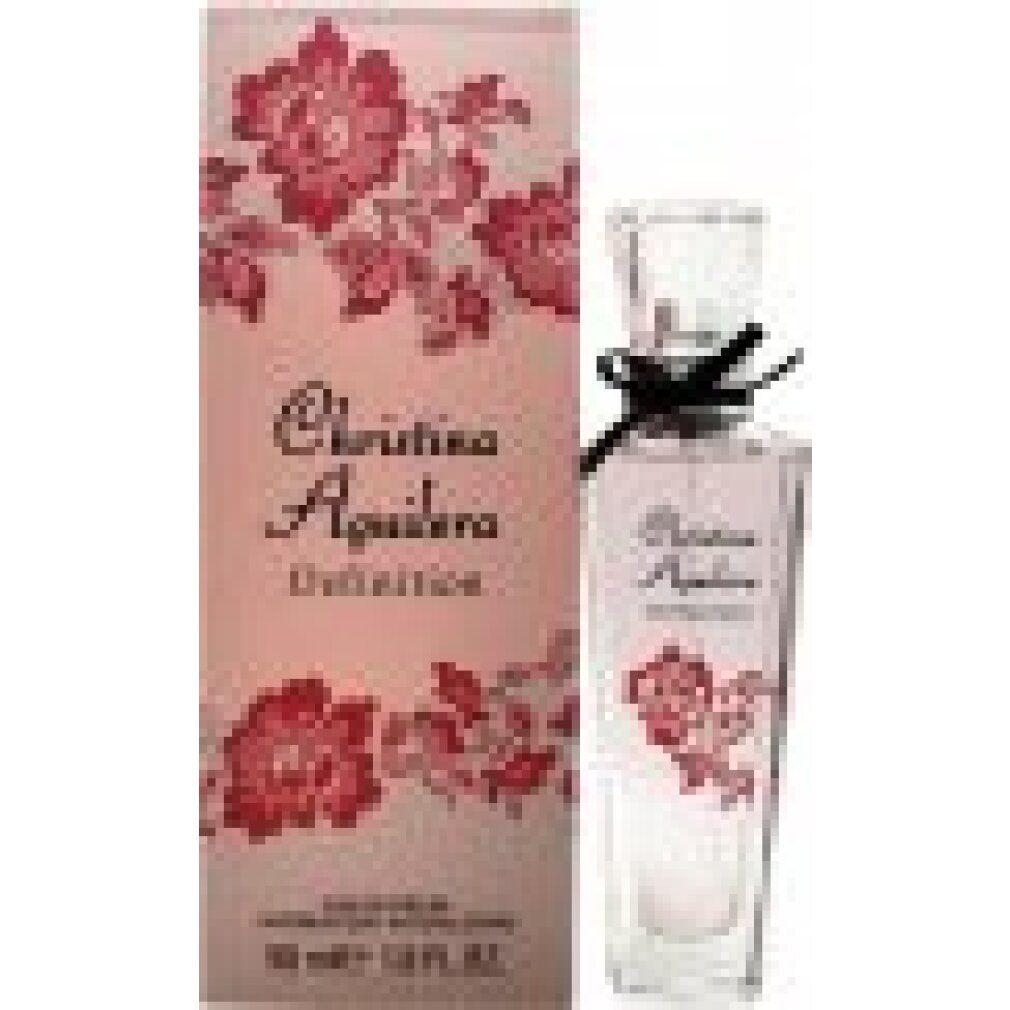 Flacone di profumo accanto alla confezione. Flacone: liquido rosa, fiocco nero. Confezione: Christina Aguilera Definition, floreale.