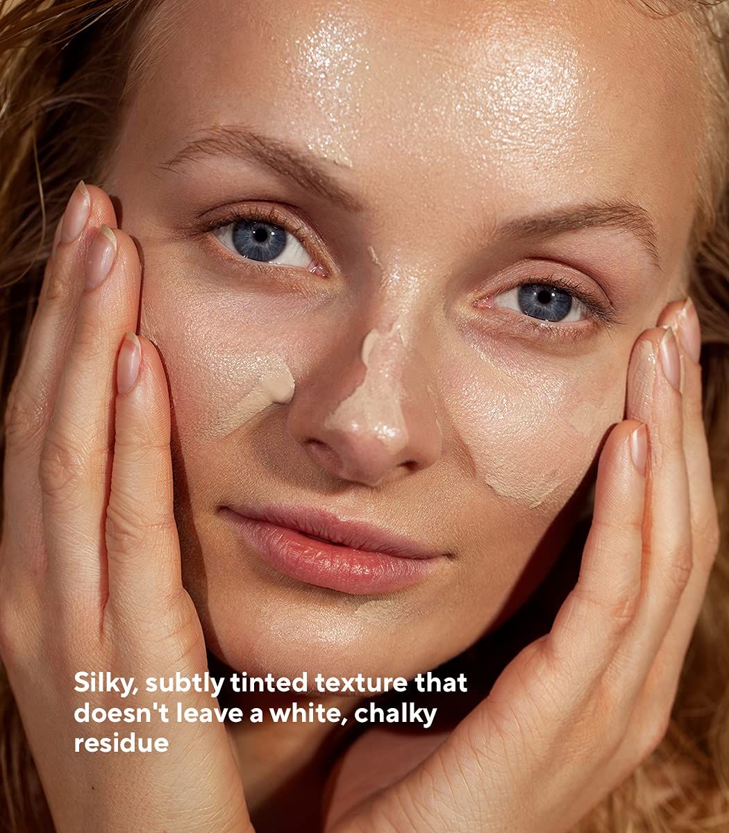 Donna con crema solare sul viso. Testo: Texture setosa, leggermente colorata, che non lascia residui bianchi e gessosi.