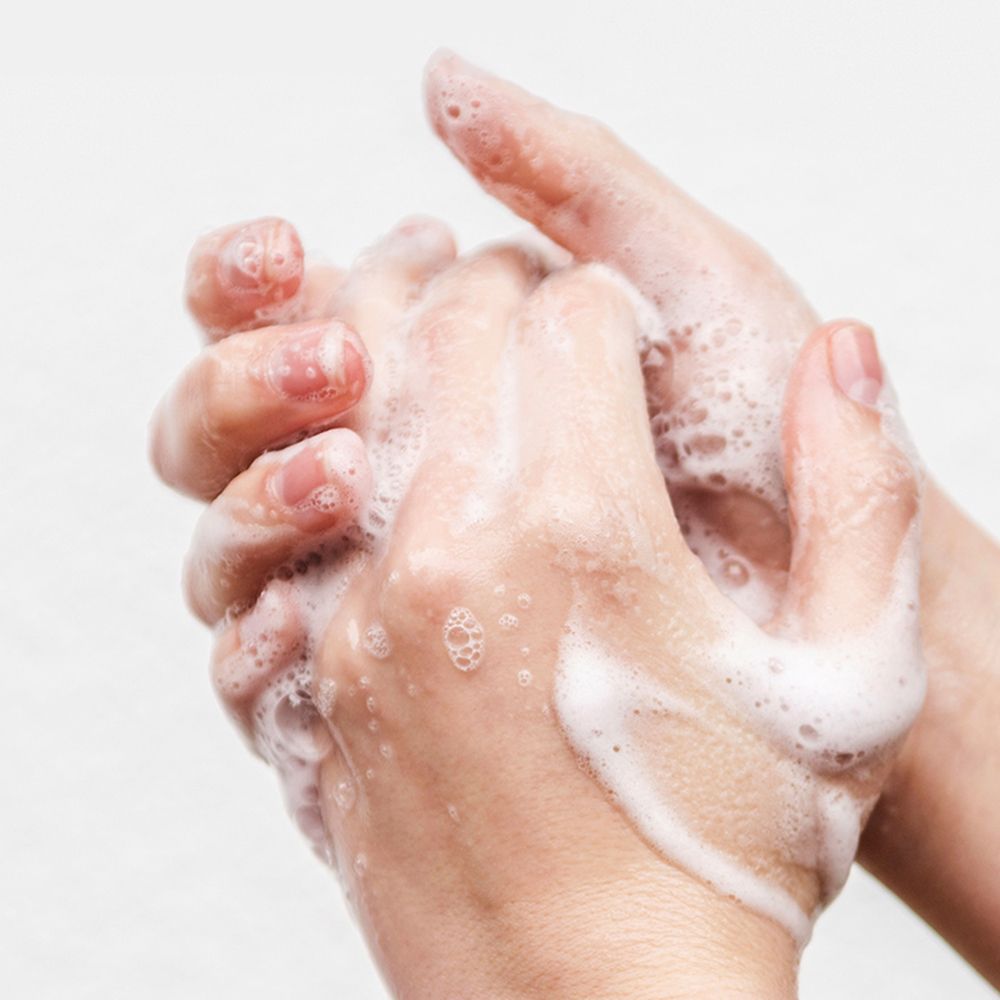 Mani coperte di schiuma di sapone. Le mani sono intrecciate e ricoperte di schiuma.