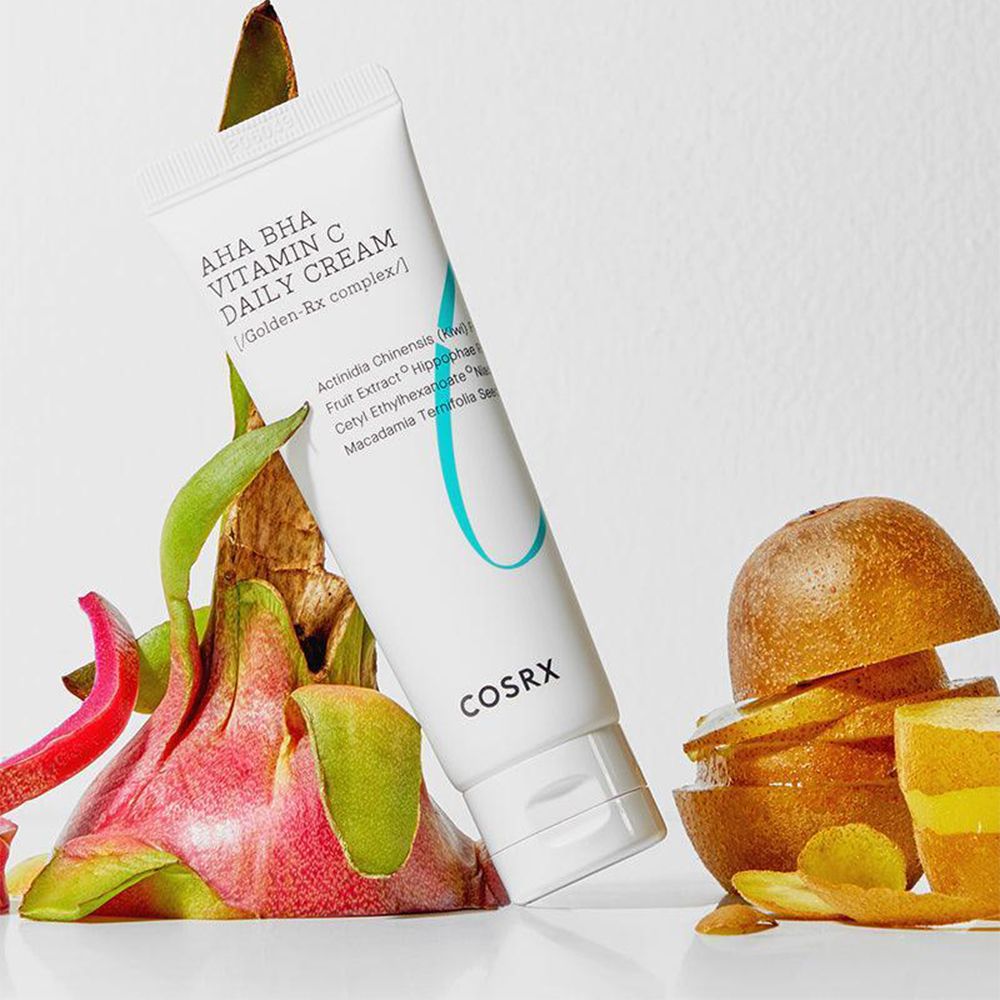 Tubo COSRX AHA BHA Vitamin C Daily Cream circondato da frutto del drago e fette di kiwi.