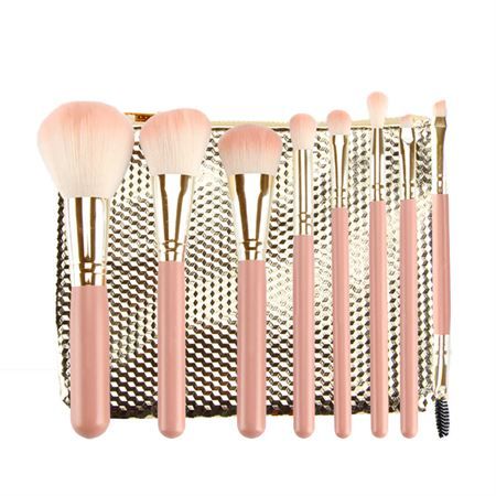 Set di otto pennelli per il trucco rosa con dettagli dorati e una pochette dorata.