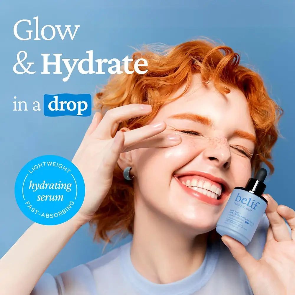 Donna sorridente con capelli rossi tiene il siero Belif Super Drops. Etichetta circolare: Siero leggero e rapido.