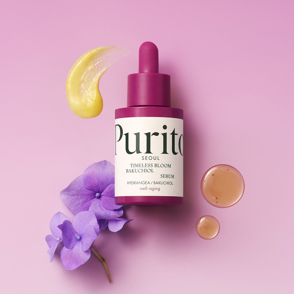 Flacone di siero Purito con contagocce, viola. Con siero giallo e fiori viola. Su sfondo rosa.