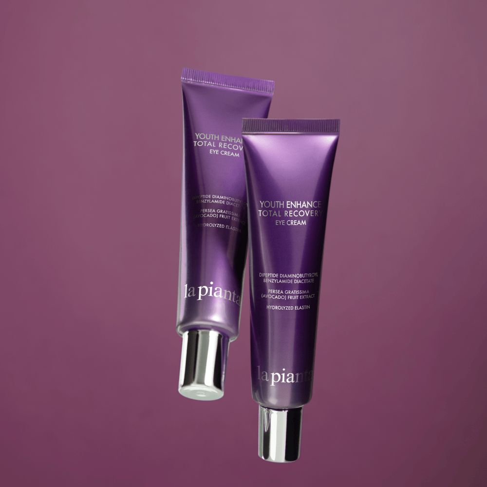 Due tubi viola con tappi bianchi. Scritta: YOUTH ENHANCE TOTAL RECOVERY EYE CREAM, la pianta.