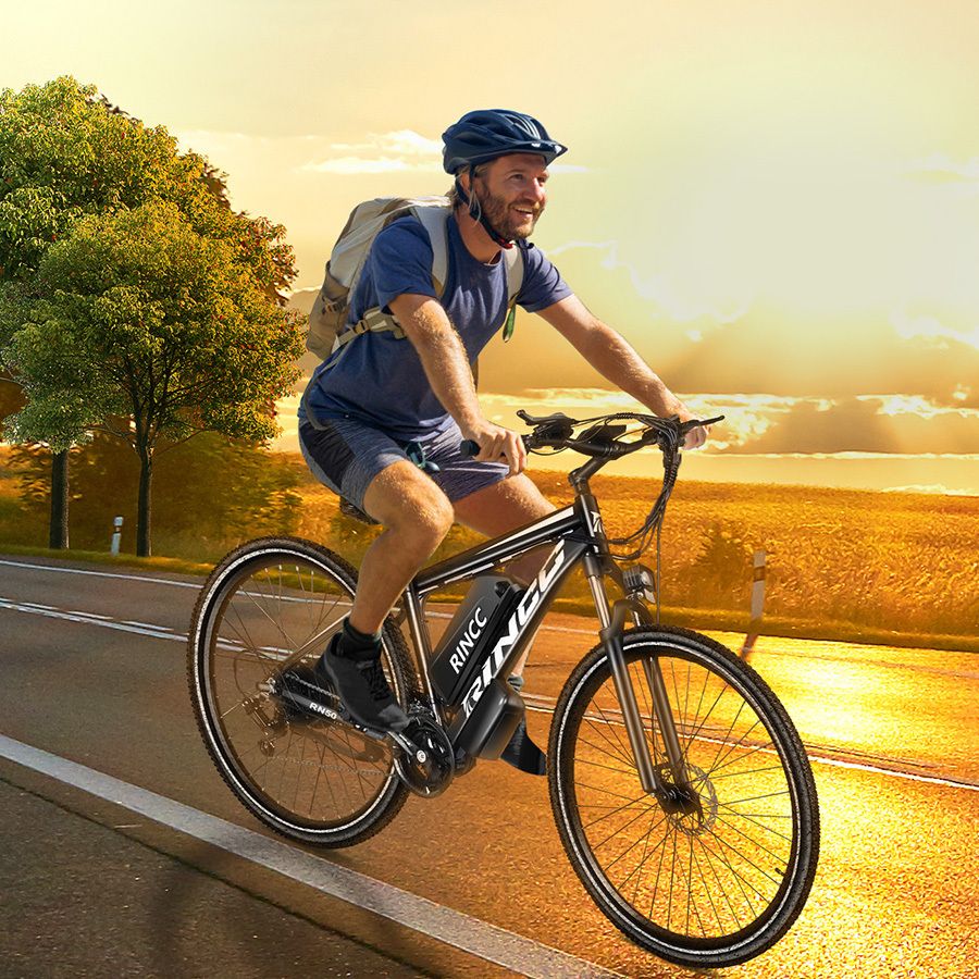 Uomo in sella a e-bike Rincc R200 su strada. Indossa casco e zaino. Paesaggio sullo sfondo.