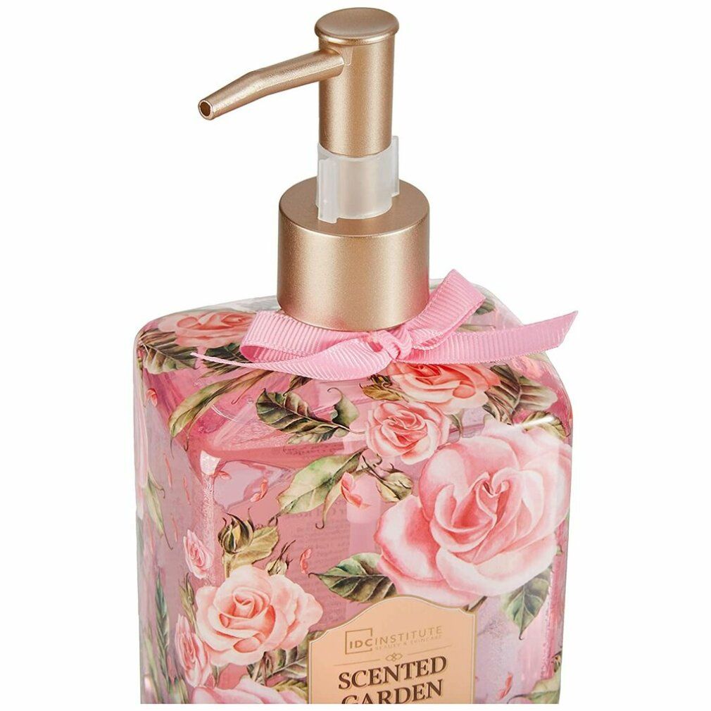Primo piano di flacone con rose, dispenser dorato e fiocco rosa. Scritta: IDC INSTITUTE Scented Garden.